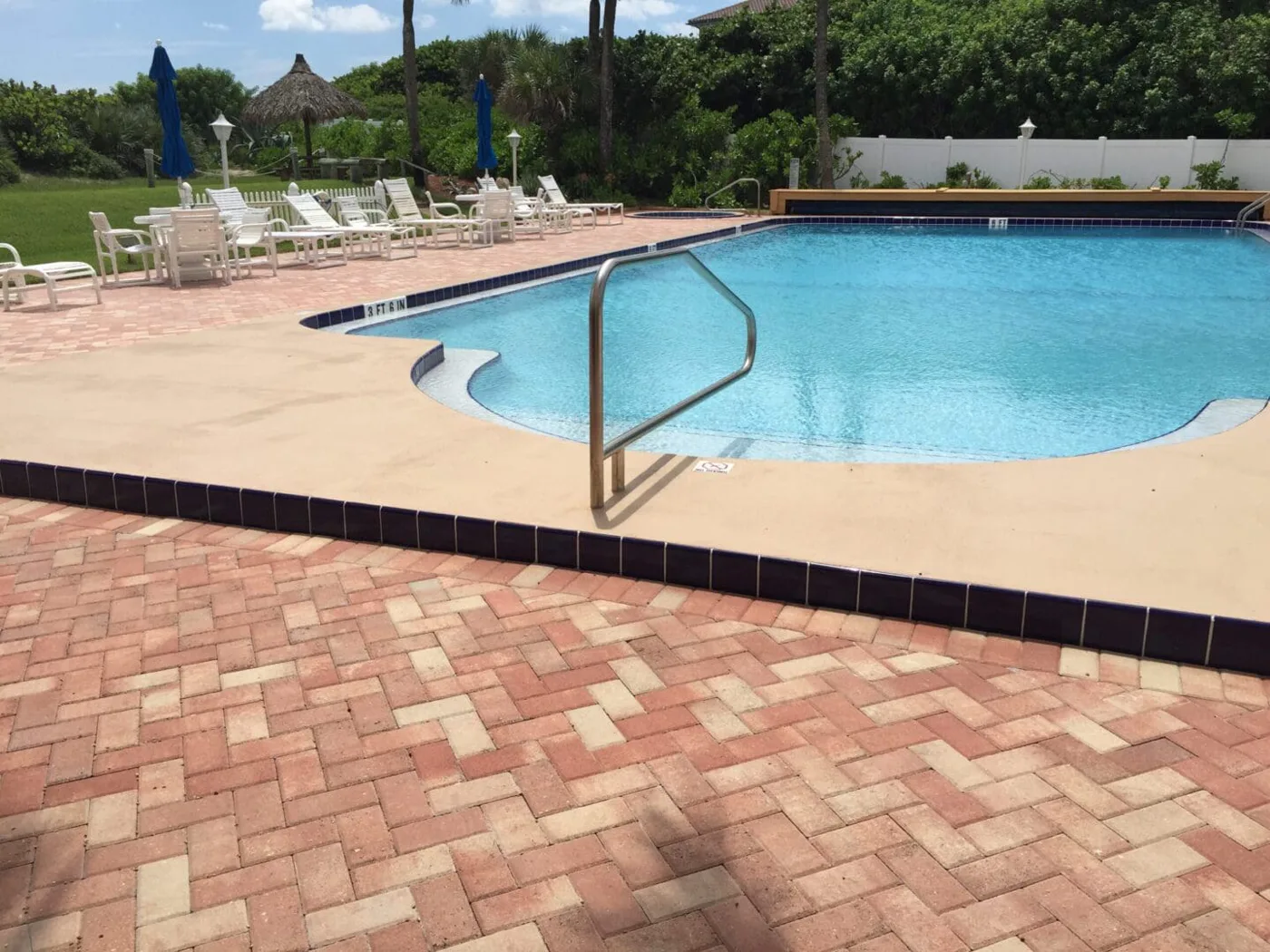 Fiberglass Pools — rectangular inground pool with brick paver deck and blue tile trim, installed by Pool Builder of Brevard
